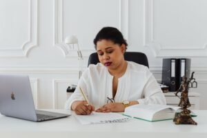 Home African American woman lawyer signing documents at a desk, symbolizing professionalism.