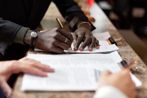 Home Close-up of hands signing documents in a business setting, emphasizing professionalism and teamwork.